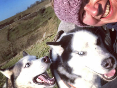 Jenny with two huskies that look like they are smiling.