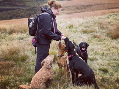 Jenny in a field with a group of dogs sitting in front of her.